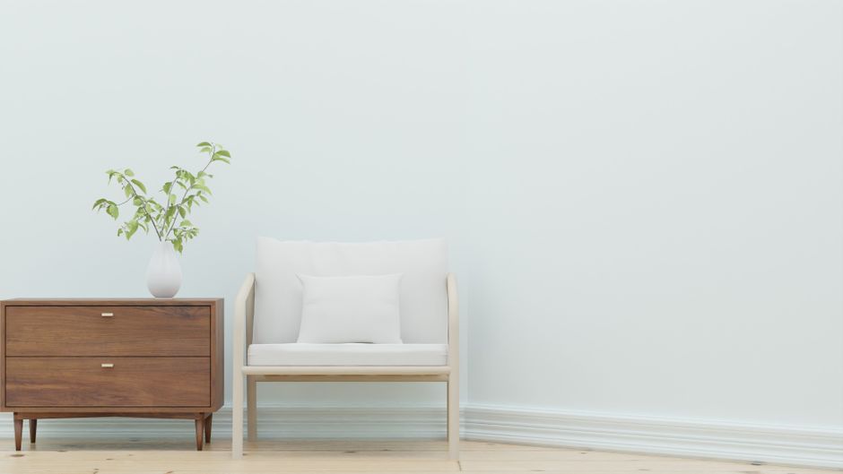 Sleek minimalist living room featuring a white armchair and wooden side table with plant.
